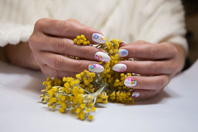 Hands with a beautiful multi-colored manicure hold a bouquet of yellow flowers