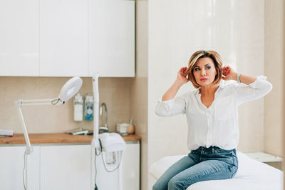 Young woman using mobile phone while standing in bathroom