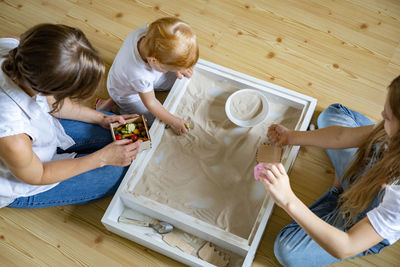 High angle view of friends sitting on wooden floor