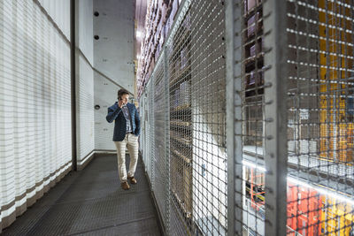 Man in automatized high rack warehouse talking on cell phone