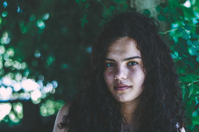 Portrait of young woman against tree