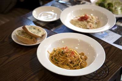 High angle view of spaghetti with garlic bread served in bowl on table