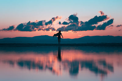 Silhouette person standing by sea against sky during sunset