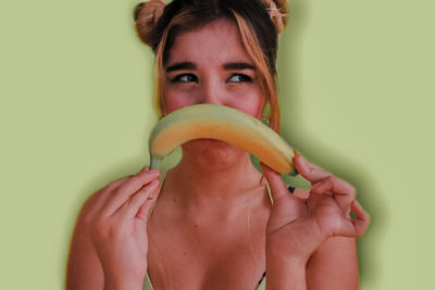 Portrait of baby girl eating fruit against wall