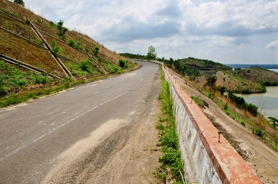 Empty road amidst land against sky