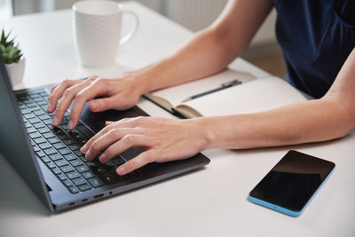 Woman working remotely from home office, using laptop