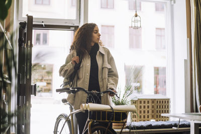 Portrait of young woman using mobile phone while sitting in cafe