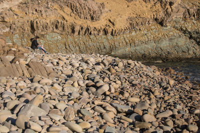 Woman sitting on rock by sea