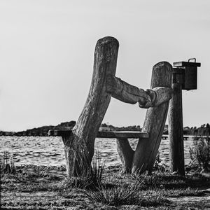 Old wooden post on field against clear sky