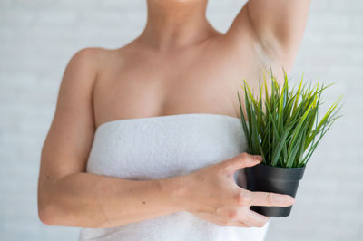 Midsection of woman holding flower against white background