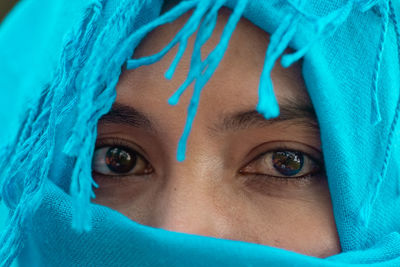 Close-up portrait of woman covering face with blue eyes