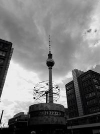 Low angle view of communications tower against cloudy sky