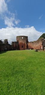Old ruin building in field against cloudy sky