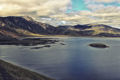 Scenic view of lake by mountains against sky