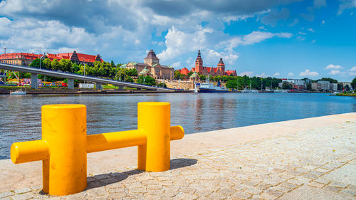 Bridge over river by buildings against sky