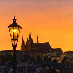 Illuminated street light in city at sunset