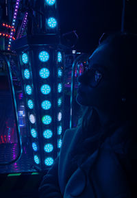 Close-up of woman wearing sunglasses by illuminated lighting equipment