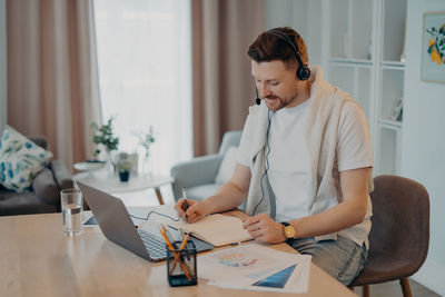 Young man using mobile phone while sitting on table at home