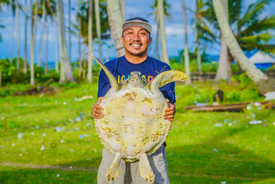 Portrait of man holding turtle outdoors