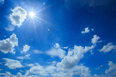 Low angle view of sunlight streaming through clouds