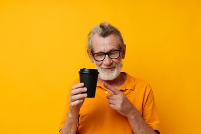 Young woman photographing against yellow background