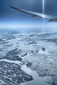 Airplane flying over snowcapped landscape against sky