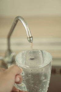 Close-up of hand pouring water in glass