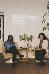 Portrait of smiling businesswomen sitting together on chairs at office