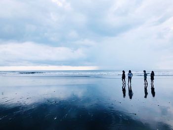 People at beach against sky