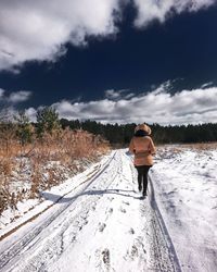 Rear view of man walking on snow covered landscape