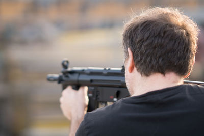 Rear view of man aiming with rifle