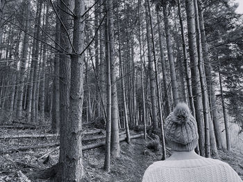 Rear view of woman amidst trees in forest