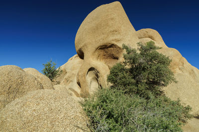 Low angle view of rock formations against clear blue sky
