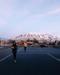 Rear view of man standing on snowcapped mountain against sky