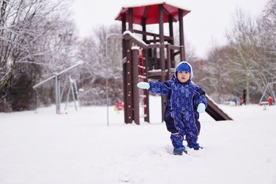 Cute boy standing on snow covered land