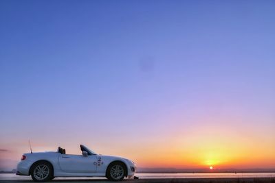 Car on sea against sky during sunset