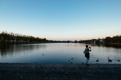 Full length of man on lake against clear blue sky