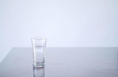 Close-up of water in glass on table against white background