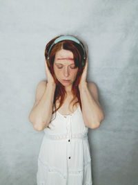 Portrait of young woman standing against wall