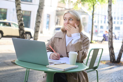 Young woman using laptop while sitting at cafe