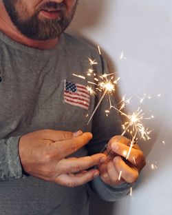 Midsection of man holding illuminated sparkler