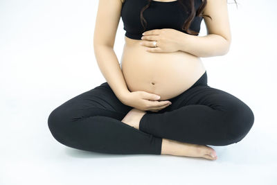 Midsection of woman sitting against white background