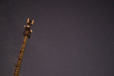 Low angle view of communications tower against star field sky at night