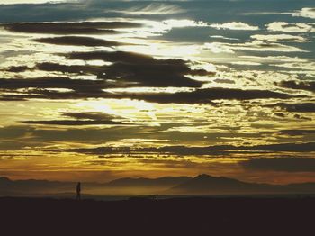 Scenic view of dramatic sky over silhouette landscape