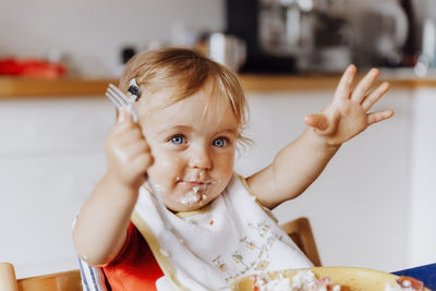 Portrait of cute baby girl having breakfast at home