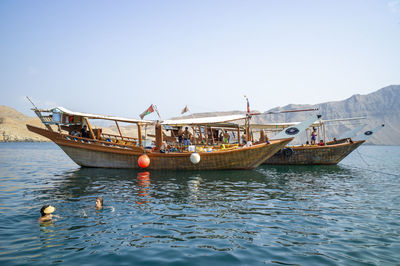Fishing boats moored in sea against clear sky