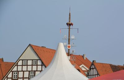 Symbols on pole amidst houses against clear sky