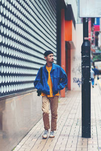 Full length portrait of young man standing on footpath