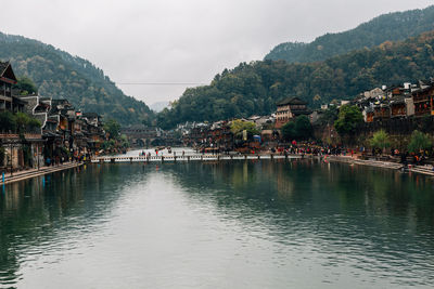 Scenic view of river by buildings against sky