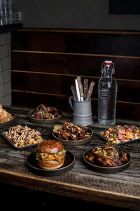 Served wooden table with appetizing burgers and chicken wings in restaurant of street food